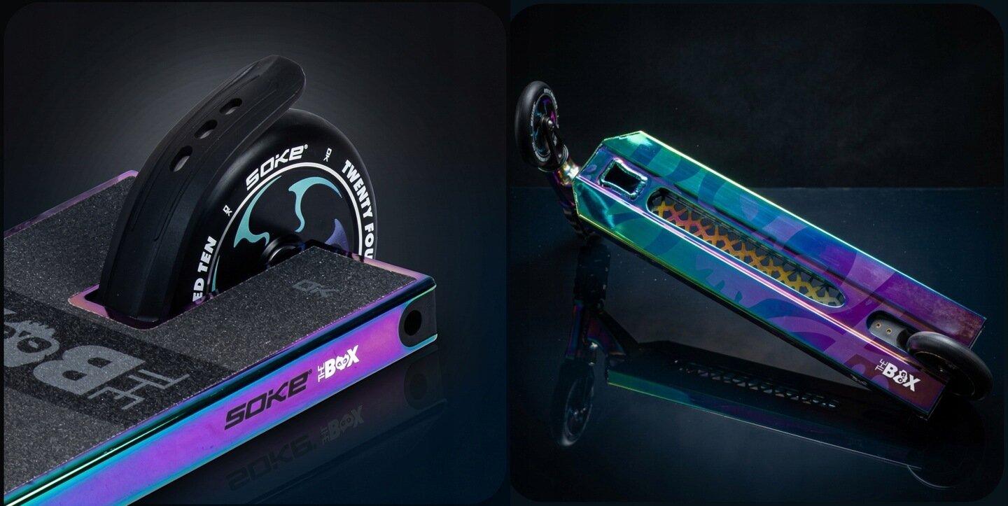 Hulajnoga wyczynowa z szerokim deckiem o wymiarach 140x553 mm, w kolorze kameleona z napisem \'SOKE\' i \'THE BOX\'. Koło z logo \'SOKE\' i wzorem graficznym, widoczne na ciemnym tle.