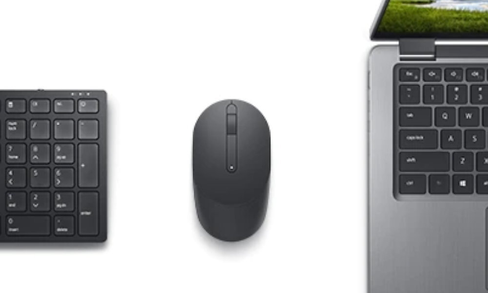 Na obrazie widoczna jest czarna klawiatura numeryczna, czarna mysz oraz fragment laptopa z klawiaturą. Ekran laptopa pokazuje krajobraz z zielonymi wzgórzami i niebem.