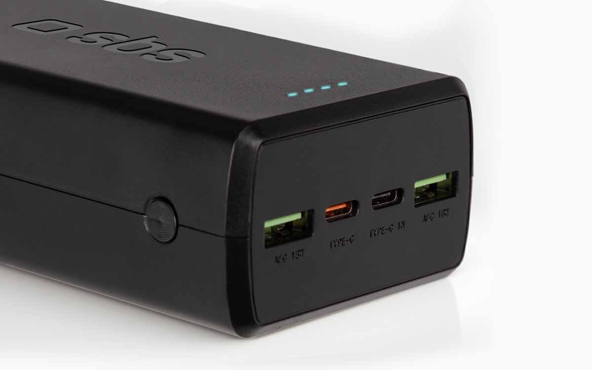 Czarny powerbank z logo \'sbs\' posiadający kilka portów: dwa USB, jeden USB-C oraz wskaźnik LED z czterema niebieskimi diodami.