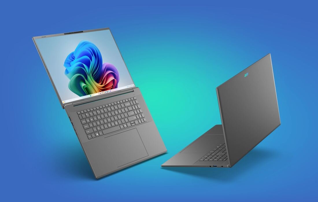 Na obrazie widoczne są dwa laptopy w kolorze szarym na niebieskim tle. Jeden z nich jest otwarty, ukazując klawiaturę i ekran z kolorową grafiką, drugi jest zamknięty, z widocznym logo producenta.