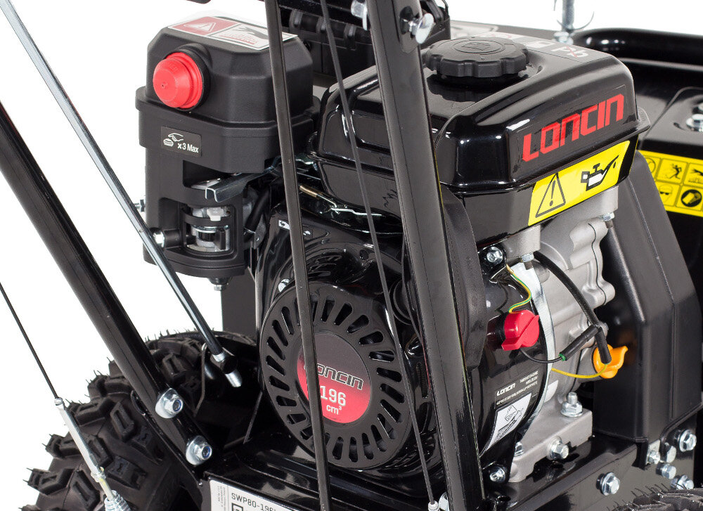 Zbliżenie na silnik urządzenia z widocznym logo \'LONCIN\' oraz oznaczeniem \'196 cm³\'. Obok znajduje się czerwony przycisk i żółty symbol ostrzegawczy.