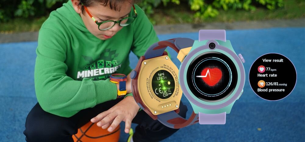 Dziecko w zielonej bluzie siedzi na niebieskiej powierzchni, trzymając piłkę do koszykówki. Obok widoczny jest smartwatch z wyświetlaczem pokazującym tętno i ciśnienie krwi: \'View result\', \'Heart rate 77 bpm\', \'Blood pressure 126/81 mmhg\'.