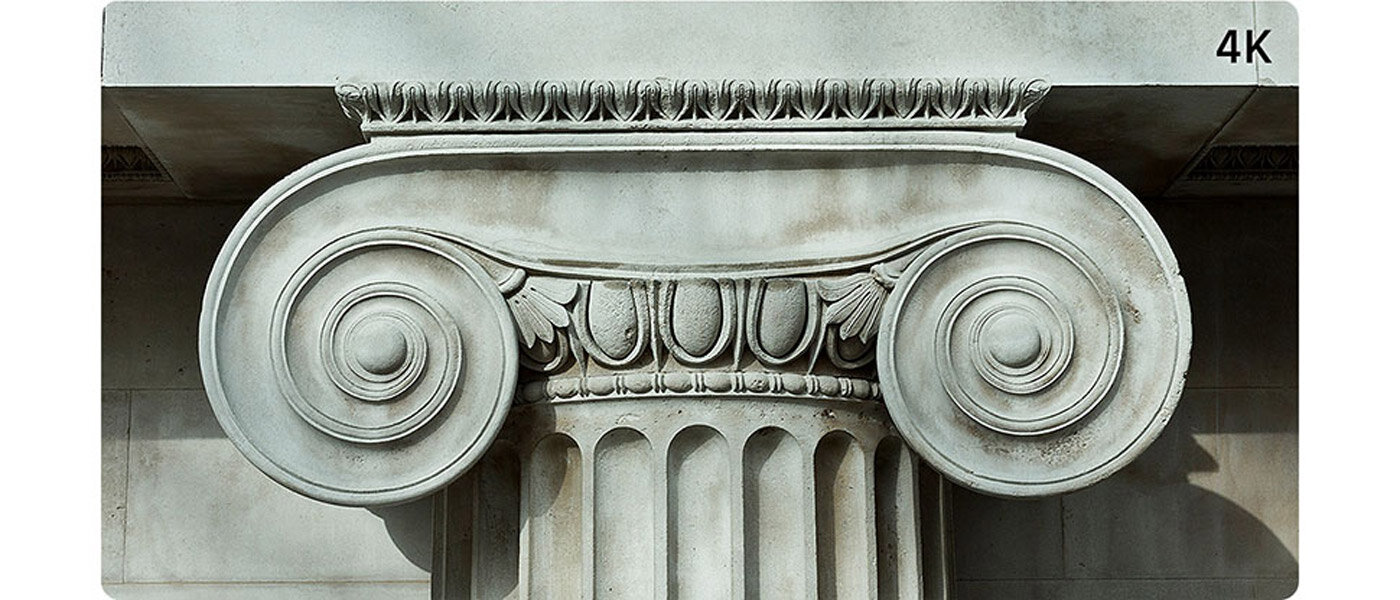 Obraz przedstawia detal architektoniczny kolumny w stylu jońskim z widocznymi spiralnymi zdobieniami. W prawym górnym rogu znajduje się napis \'4K\'.