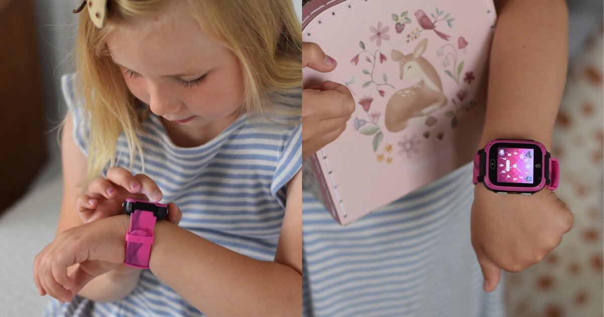 Dziecko w paskowanej koszulce nosi różowy smartwatch na nadgarstku. Obok widoczna jest różowa książka z ilustracją jelenia i kwiatów.