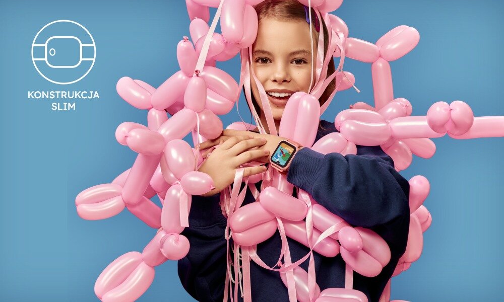 Osoba otoczona różowymi balonami nosi smartwatch na nadgarstku. Obok znajduje się symbol zegarka z napisem \'KONSTRUKCJA SLIM\'.