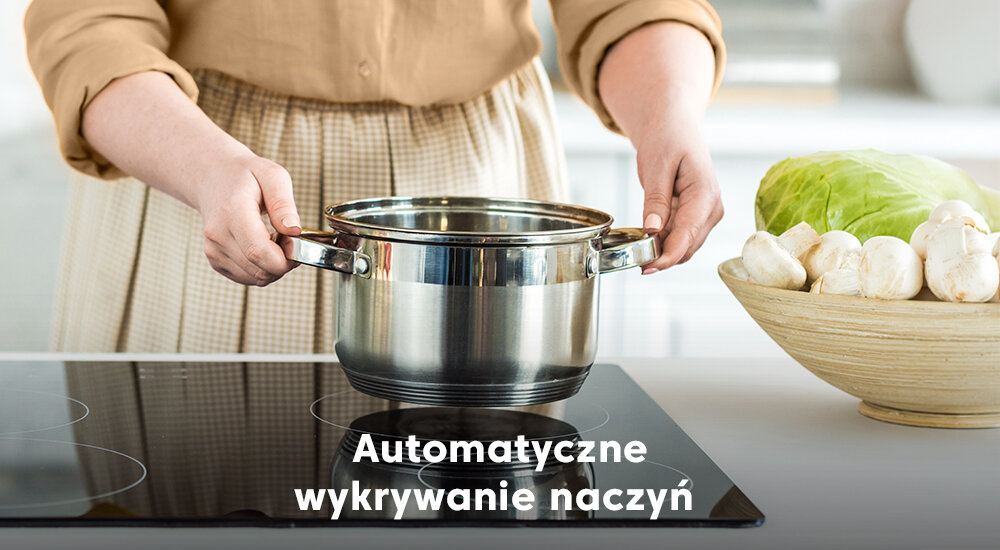 Osoba trzyma garnek nad płytą indukcyjną, obok znajduje się miska z kapustą i pieczarkami. Na obrazie widoczny jest tekst: \'Automatyczne wykrywanie naczyń\'.