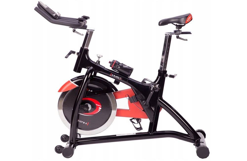 Rower spinningowy w kolorze czarnym z czerwonymi akcentami, posiada koło zamachowe i regulowane siodełko. Na ramie widoczne jest logo \'HMS\'.