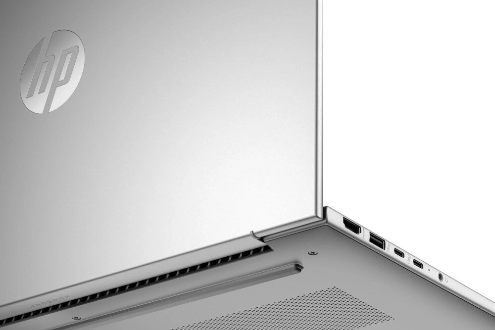 Srebrny laptop z widocznym logo \'hp\' na pokrywie. Widoczne są porty: HDMI, USB i USB-C oraz otwory wentylacyjne na spodzie urządzenia.