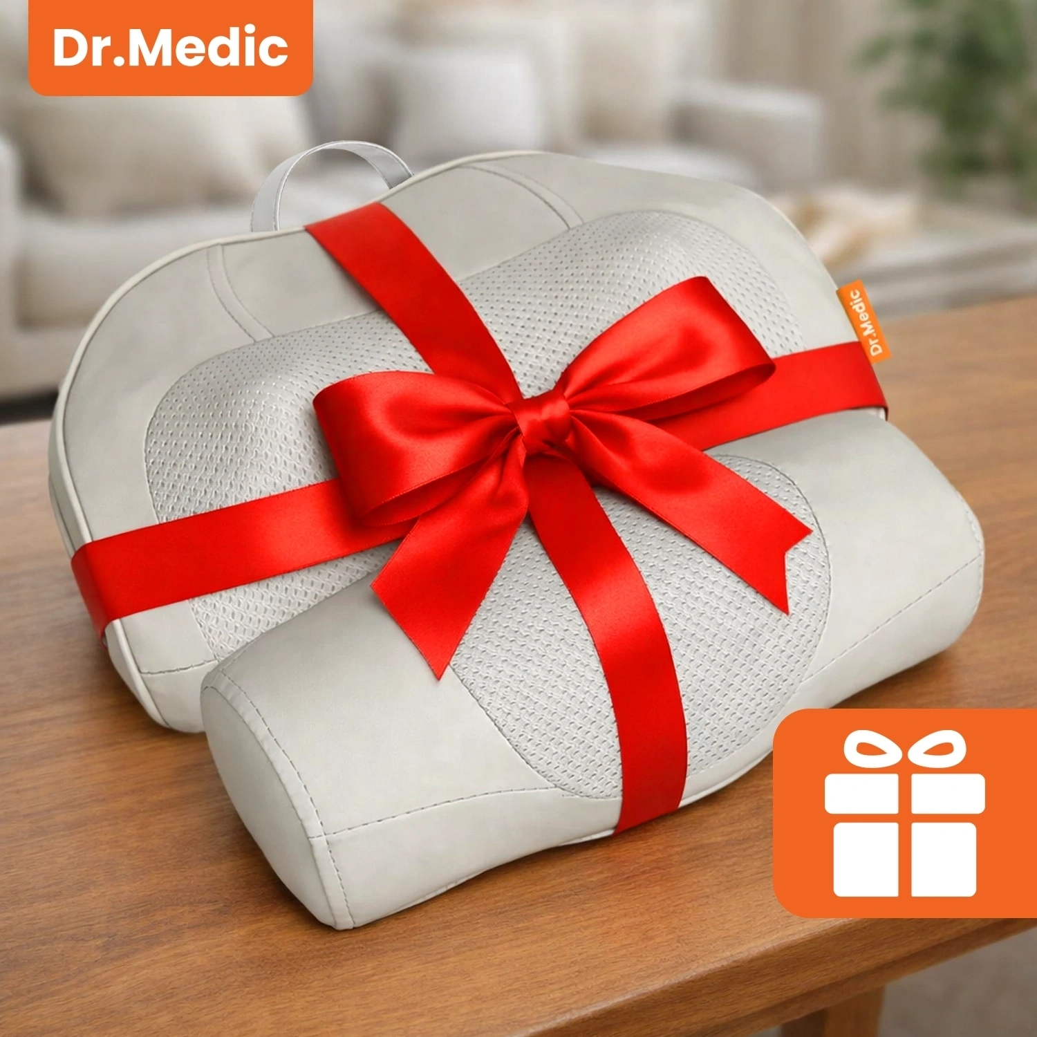 Poduszka masująca w kolorze szarym z czerwonym kokardą leży na drewnianym stole. W lewym górnym rogu widoczne jest logo \'Dr.Medic\'.
