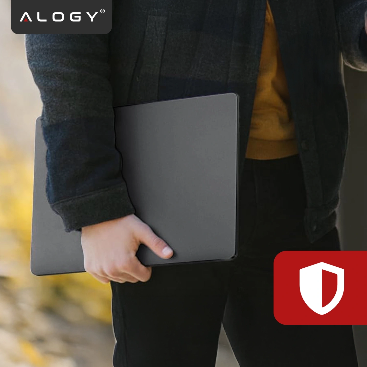 Osoba trzyma czarne etui na laptopa, a w lewym górnym rogu widoczne jest logo \'ALOGY\'. W prawym dolnym rogu znajduje się czerwony symbol tarczy.