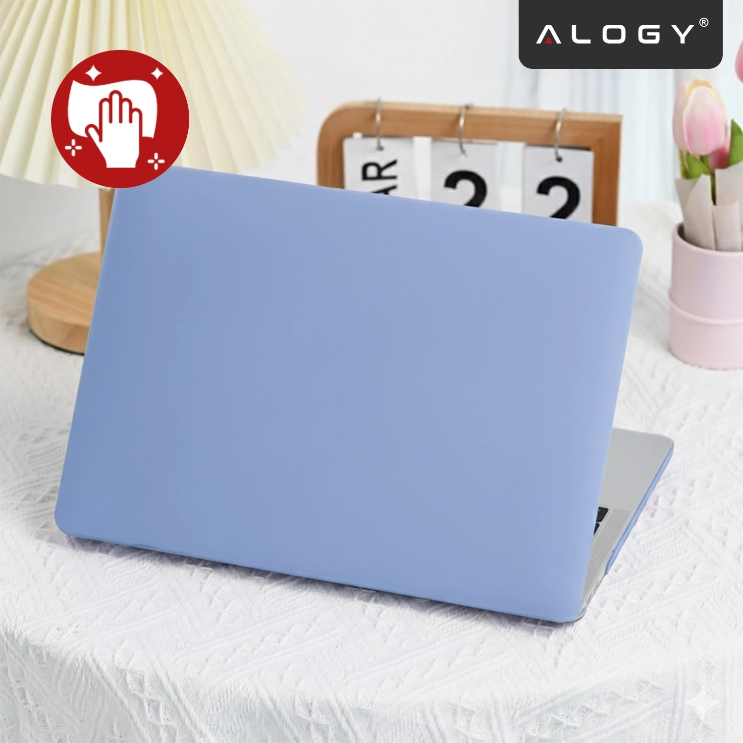 Na obrazie widoczny jest laptop z lawendowym etui na białym obrusie, obok stoi lampa i kalendarz. W prawym górnym rogu znajduje się logo \'ALOGY\'.