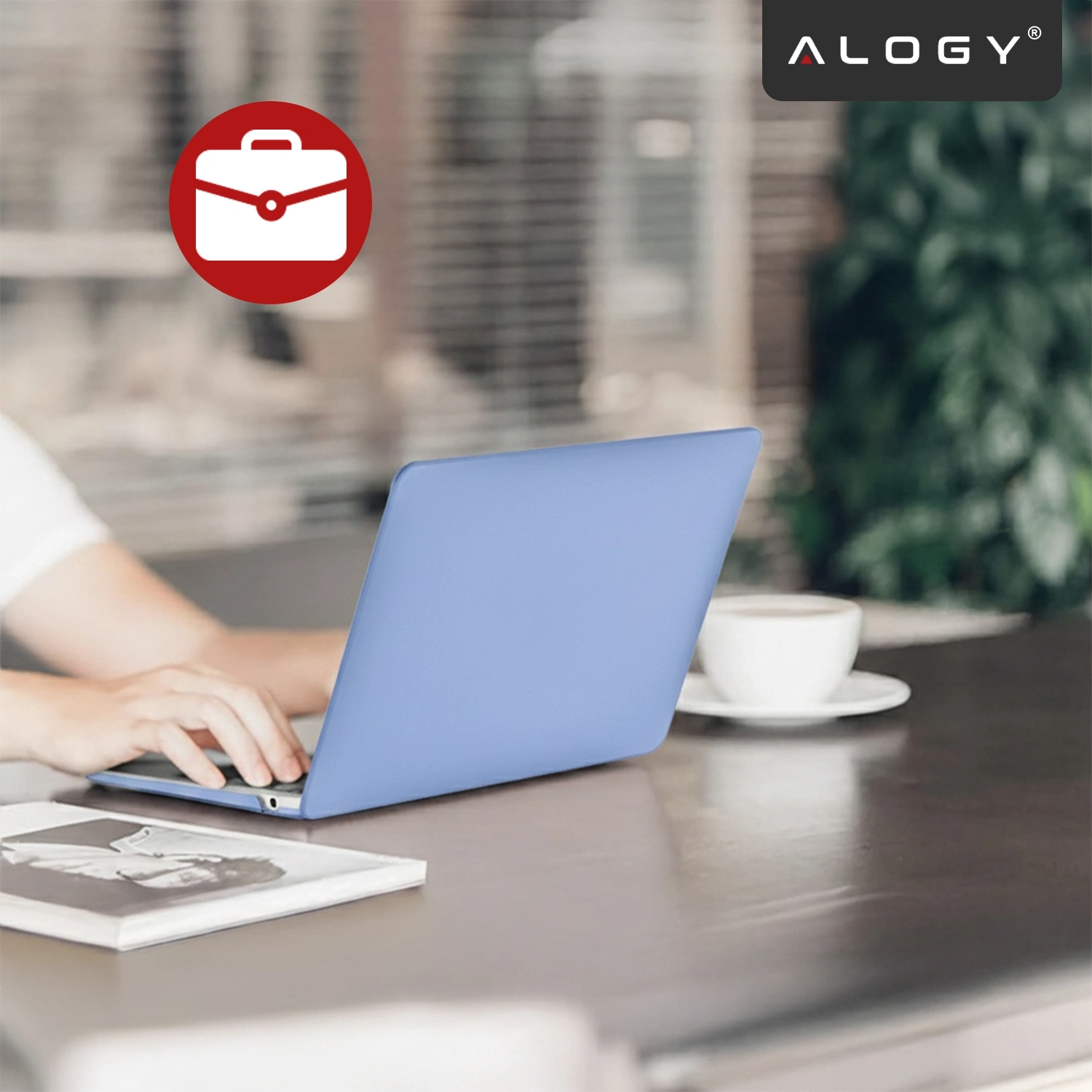 Osoba korzysta z laptopa z lawendowym etui na biurku, obok znajduje się filiżanka kawy. W prawym górnym rogu widoczne jest logo \'ALOGY\'.