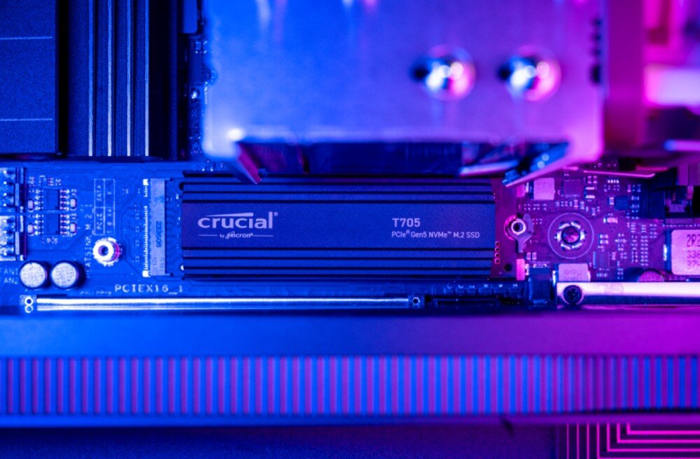 Na obrazie widoczny jest dysk SSD z radiatorem, na którym znajduje się napis \'crucial T705 PCIe Gen3 NVMe M.2 SSD\'. Dysk jest zamontowany na płycie głównej, a całość oświetlona jest niebiesko-różowym światłem.