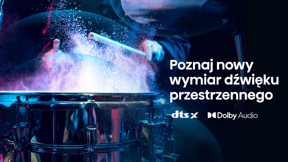 Obraz przedstawia perkusję uderzaną pałeczką, z efektem rozpryskującego się pyłu. Obok znajduje się tekst: \'Poznaj nowy wymiar dźwięku przestrzennego\', oraz logotypy \'dts X\' i \'Dolby Audio\'.