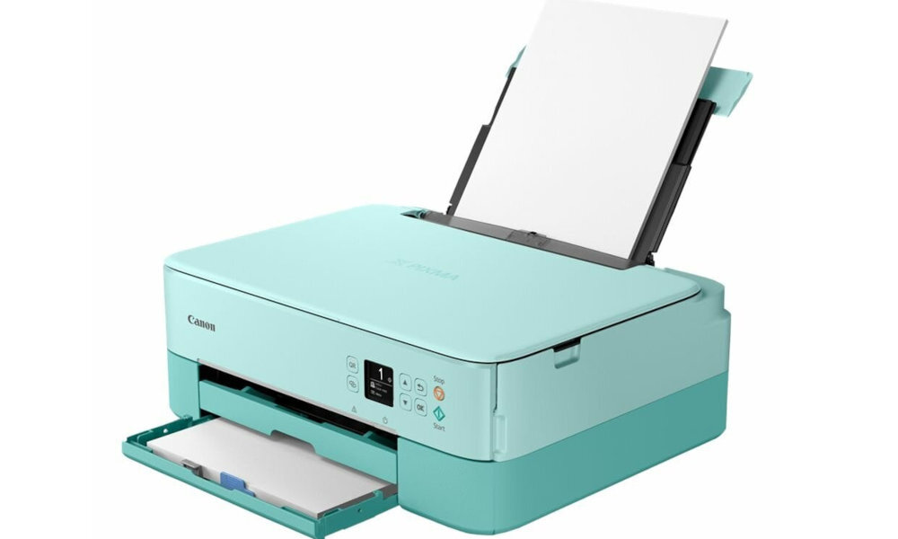 Jasnoniebieskie urządzenie wielofunkcyjne z otwartą tacą na papier i panelem sterowania z wyświetlaczem. Na obudowie widoczne jest logo Canon.