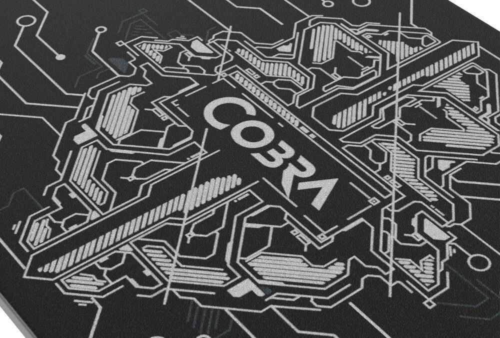 Obraz przedstawia czarną powierzchnię z białym, geometrycznym wzorem przypominającym obwody elektroniczne. Na środku widoczny jest napis \'COBRA\'.