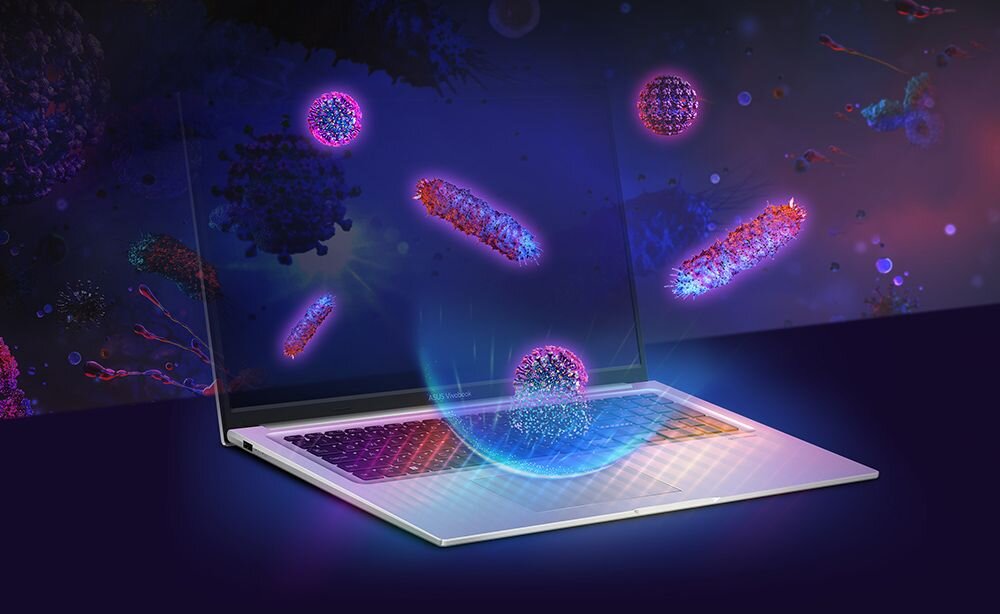 Laptop z otwartym ekranem, na którym widoczne są kolorowe, abstrakcyjne kształty przypominające mikroorganizmy. Tło jest ciemne, a klawiatura laptopa jest podświetlona różnymi kolorami.