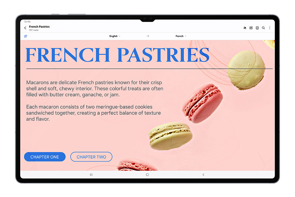 Tablet wyświetla stronę z tekstem o francuskich makaronikach, z tytułem \'FRENCH PASTRIES\' i przyciskami \'CHAPTER ONE\' oraz \'CHAPTER TWO\'. Na ekranie widoczne są kolorowe makaroniki na różowym tle.