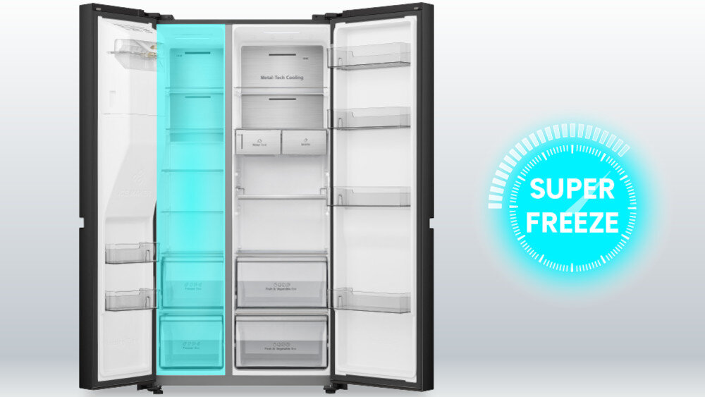 Otwarta lodówka z widocznymi półkami i szufladami, z napisem \'Metal Tech Cooling\' na jednej z półek. Obok lodówki znajduje się niebieski symbol z napisem \'SUPER FREEZE\'.