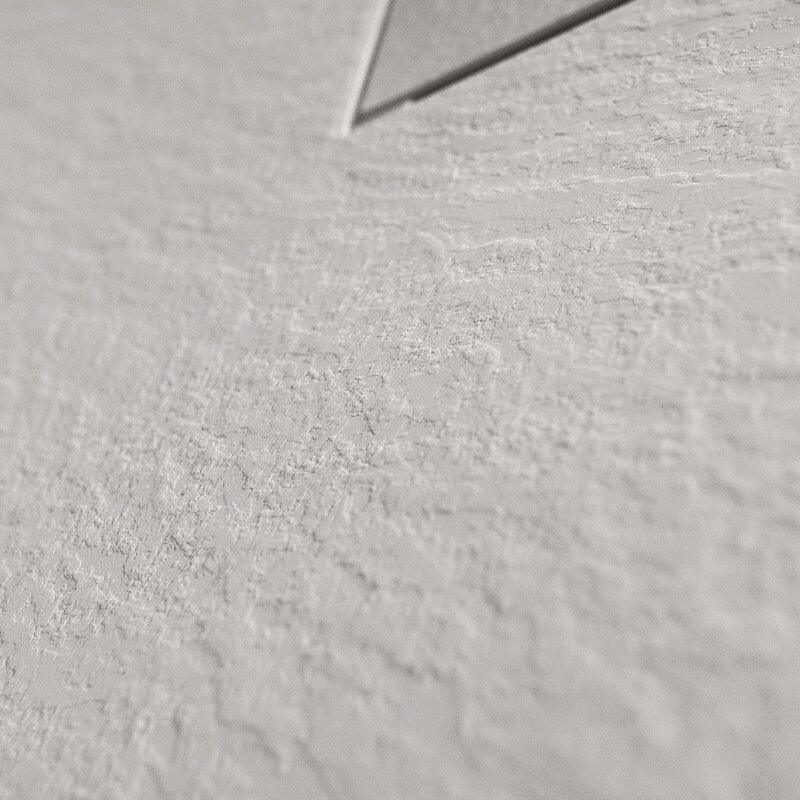Zbliżenie na białą, teksturowaną powierzchnię z widocznym fragmentem metalowego elementu w rogu.