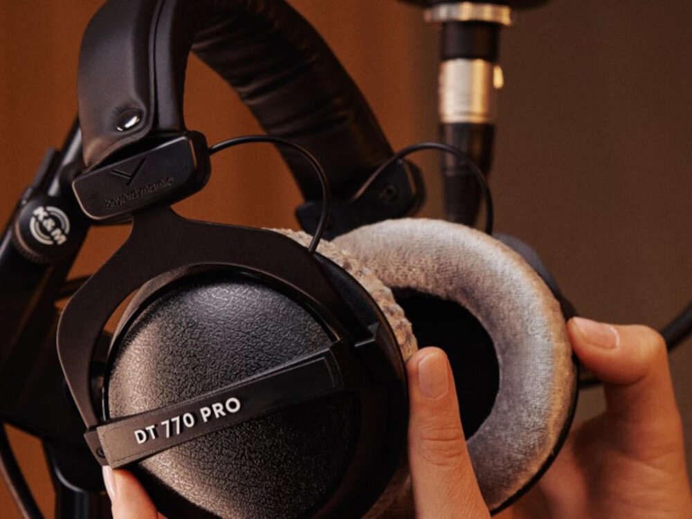Osoba trzyma czarne słuchawki nauszne z widocznym napisem \'DT 770 PRO\' oraz logo \'beyerdynamic\'.