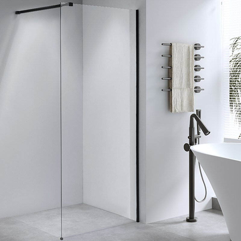Nowoczesna łazienka z przeszkloną ścianką prysznicową typu walk-in oraz wolnostojącą baterią przy wannie. Na ścianie znajduje się wieszak z ręcznikiem, a przez okno wpada naturalne światło.
