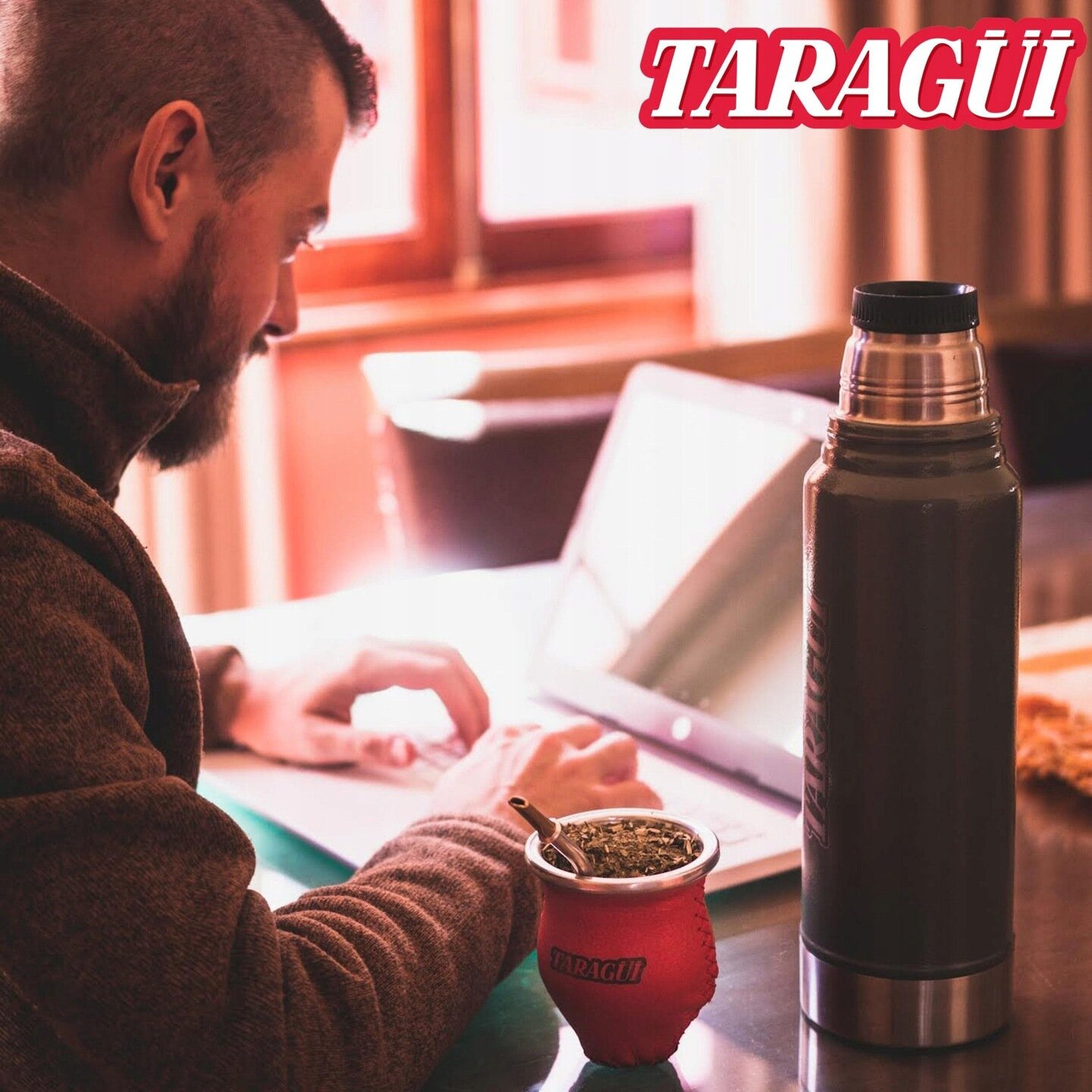 Osoba pracuje na laptopie, obok stoi termos i naczynie z yerba mate. W prawym górnym rogu widoczne jest logo \'TARAGÜI\'.