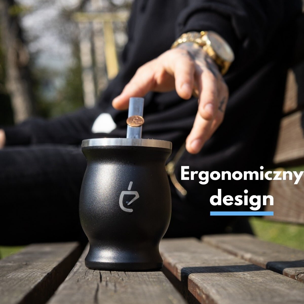 Czarna tykwa z metalowym obrzeżem i logo w kształcie stylizowanej litery \'e\', z bombillą w środku. Obok widoczny jest napis \'Ergonomiczny design\'.