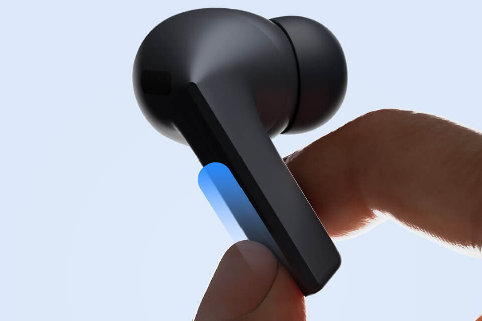 Palec przesuwa się po ostrzu pojedynczych, czarnych Galaxy Buds3 FE. Czarna słuchawka dokanałowa trzymana w palcach, z widocznym niebieskim elementem na obudowie. Tło jest jasne, jednolite.