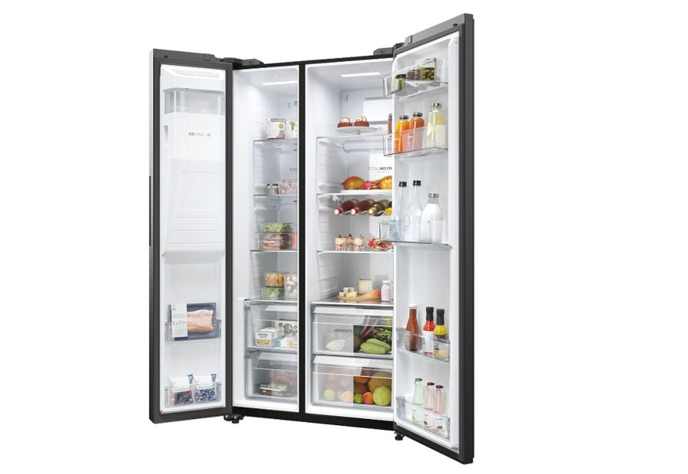 Otwarta lodówka z widocznymi półkami wypełnionymi różnorodnymi produktami spożywczymi, takimi jak owoce, warzywa, napoje i sosy. Wewnątrz drzwi znajdują się dodatkowe półki z butelkami i słoikami.