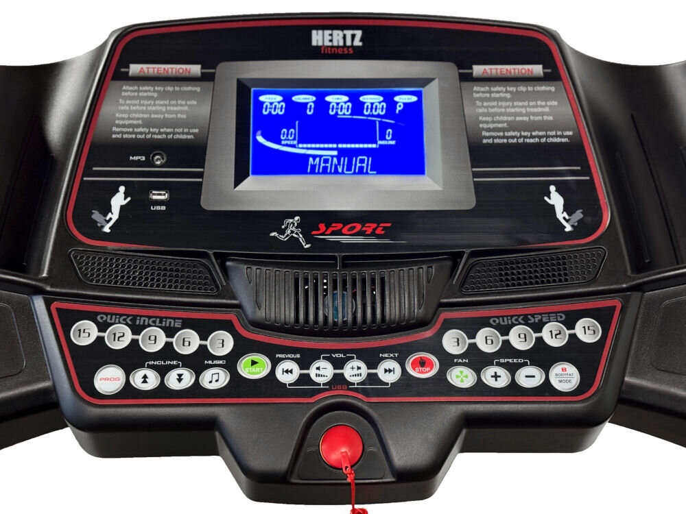 Panel sterowania bieżni z wyświetlaczem LCD pokazującym napis \'MANUAL\' oraz przyciskami do regulacji nachylenia i prędkości. Widoczne logo \'HERTZ fitness\' oraz ikony funkcji takich jak USB i MP3.