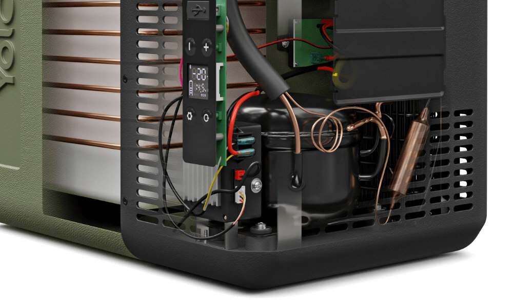 Widoczny jest fragment wnętrza lodówki turystycznej z elementami elektronicznymi i przewodami. Na obudowie znajduje się logo \'yolco\'.