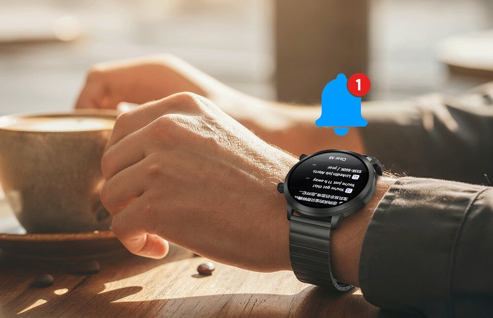 Osoba trzyma filiżankę kawy, na nadgarstku ma czarny smartwatch z wyświetlaczem pokazującym tekst. Obok zegarka widoczna jest ikona dzwonka z czerwoną jedynką, sugerująca powiadomienie.