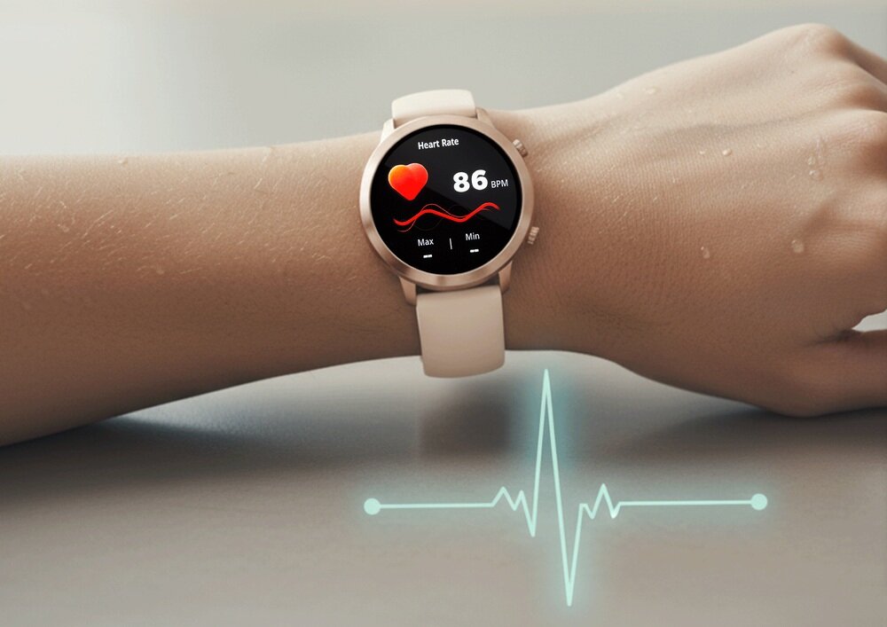 Na zdjęciu widoczny jest smartwatch na nadgarstku, wyświetlający pomiar tętna z wartością 86 BPM. Obok zegarka znajduje się graficzna reprezentacja wykresu EKG.