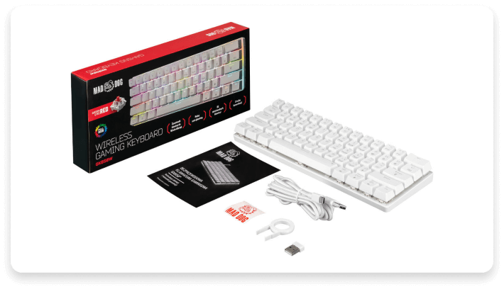 Na obrazie znajduje się biała klawiatura bezprzewodowa z akcesoriami, takimi jak kabel, adapter USB i instrukcja. Obok klawiatury widoczne jest pudełko z napisem \'MAD DOG\' oraz \'WIRELESS GAMING KEYBOARD\'.