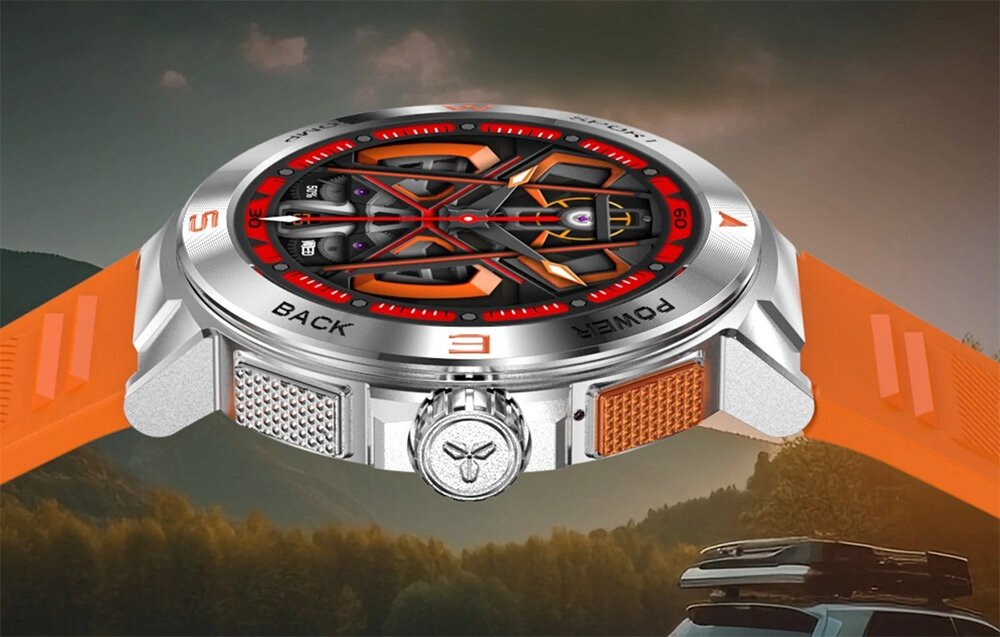 Smartwatch z pomarańczowym paskiem i srebrną kopertą, z widocznymi oznaczeniami \'BACK\' i \'POWER\' na tarczy. W tle widać krajobraz z górami i drzewami.
