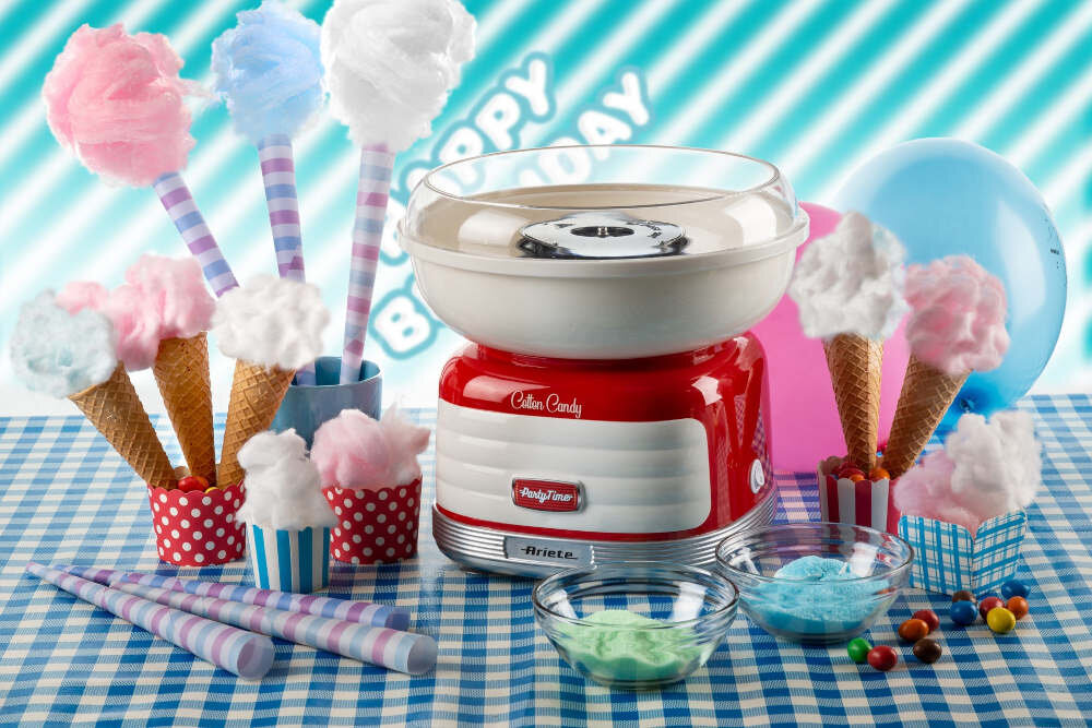 Na obrazie znajduje się maszyna do waty cukrowej w stylu retro z napisem \'Cotton Candy Party Time\' oraz \'Ariete\'. Wokół niej są różnokolorowe waty cukrowe na patykach i w rożkach, a także miseczki z kolorowym cukrem i balon w tle.