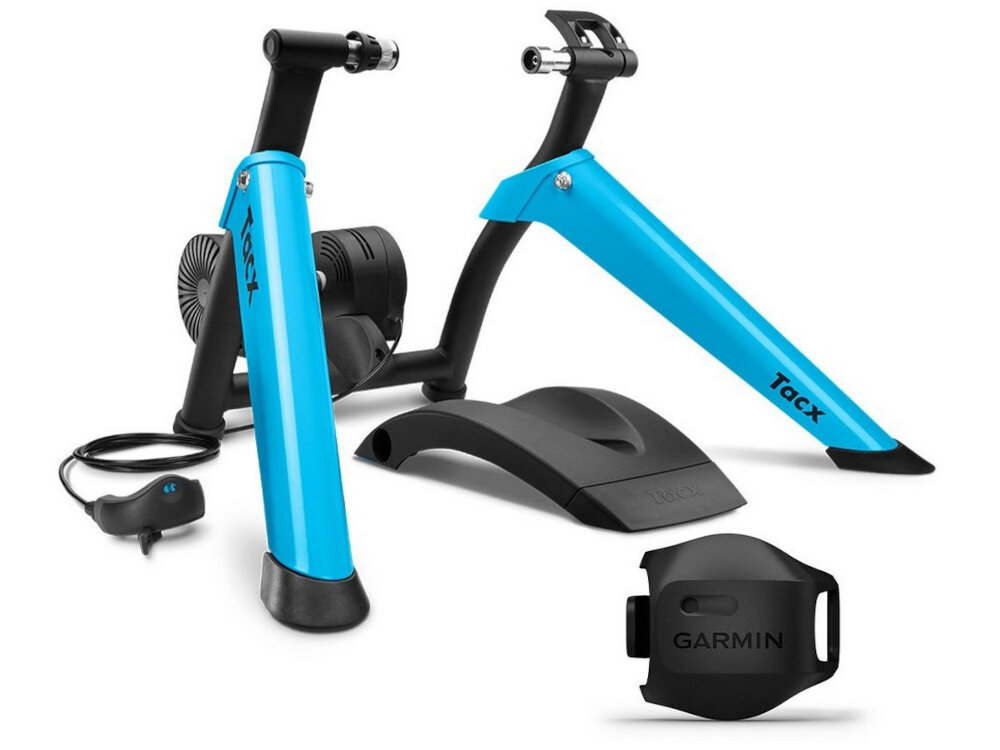 Na obrazie widoczny jest trenażer rowerowy z niebieskimi ramionami i czarnymi elementami, obok którego znajduje się czujnik z napisem \'GARMIN\'.