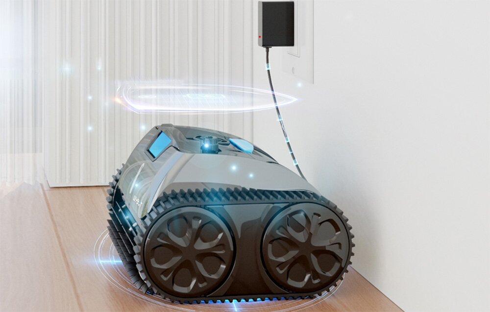 Na obrazie widoczny jest robot do czyszczenia basenów z dużymi kołami, podłączony do ładowarki w gniazdku ściennym. W tle znajduje się jasna zasłona.
