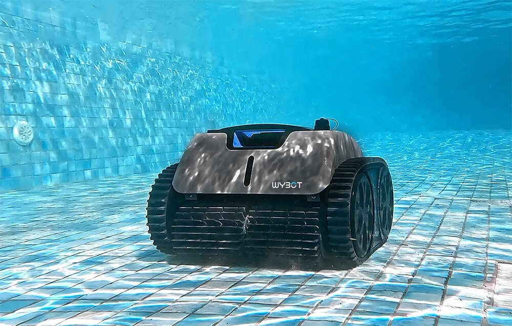 Robot do czyszczenia basenów porusza się po dnie basenu, otoczony wodą. Na urządzeniu widoczne jest logo \'WYBOT\'.