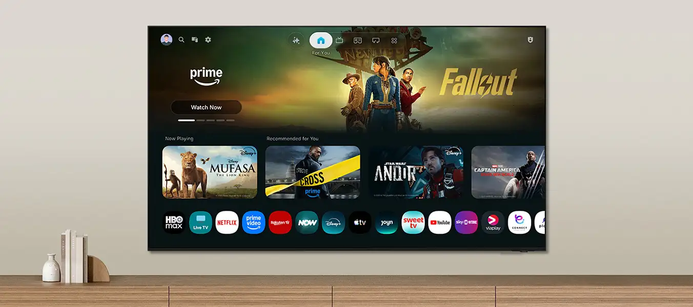 2026-one-ui-tizen-pc-eu 1352x600 Telewizor wyświetla ekran główny z aplikacjami streamingowymi, takimi jak HBO max, Netflix, i prime video. Na ekranie widoczne są również miniatury filmów, w tym \'Mufasa\' i \'Andor\'.