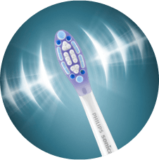 Główka szczoteczki sonicznej z białymi i niebieskimi elementami na tle z efektem świetlnym. Na trzonku widoczny napis \'PHILIPS SONICARE\'.