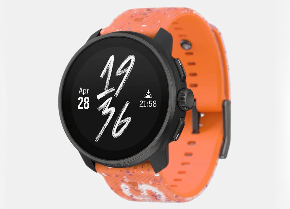 Smartwatch z okrągłym, czarnym wyświetlaczem pokazującym datę \'Apr 28\' i czas \'21:58\'. Pasek jest pomarańczowy z białymi wzorami.
