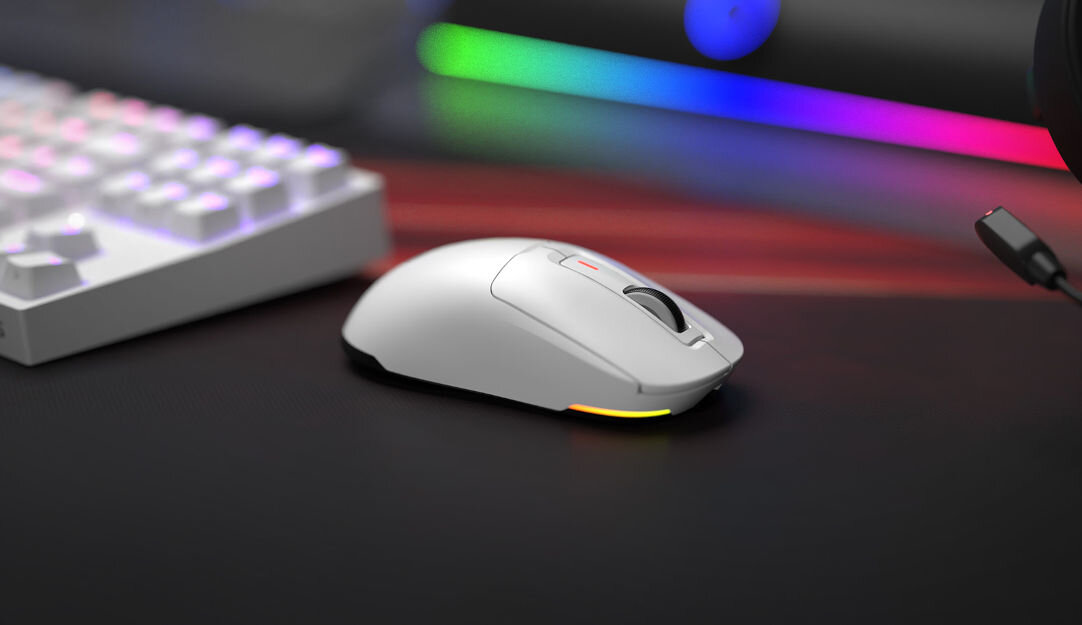 Na obrazie widoczna jest biała mysz komputerowa z podświetleniem RGB, umieszczona na ciemnej powierzchni. W tle znajduje się klawiatura oraz elementy z kolorowym podświetleniem.