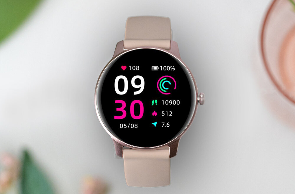Smartwatch z różowym paskiem wyświetla na ekranie czas 09:30, datę 05/08 oraz informacje o tętnie, poziomie naładowania baterii, liczbie kroków, spalonych kaloriach i dystansie. Tło jest rozmyte, z widocznymi elementami roślinnymi i naczyniem.