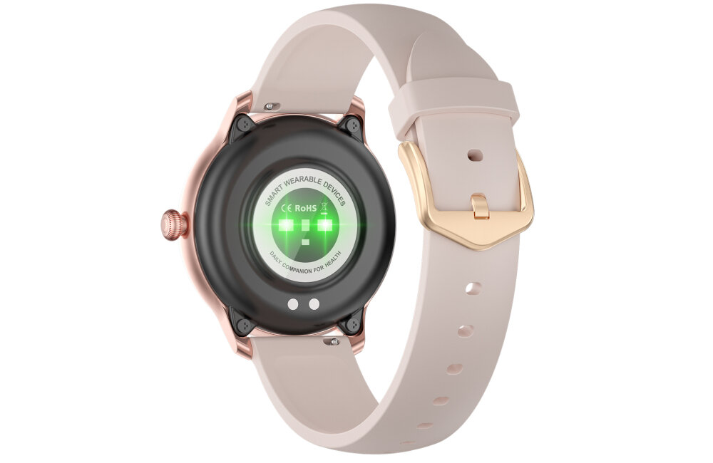 Obraz przedstawia tył różowego smartwatcha z okrągłym czarnym panelem i zielonymi diodami. Na panelu widoczny jest tekst: \'SMART WEARABLE DEVICES CE RoHS\'.