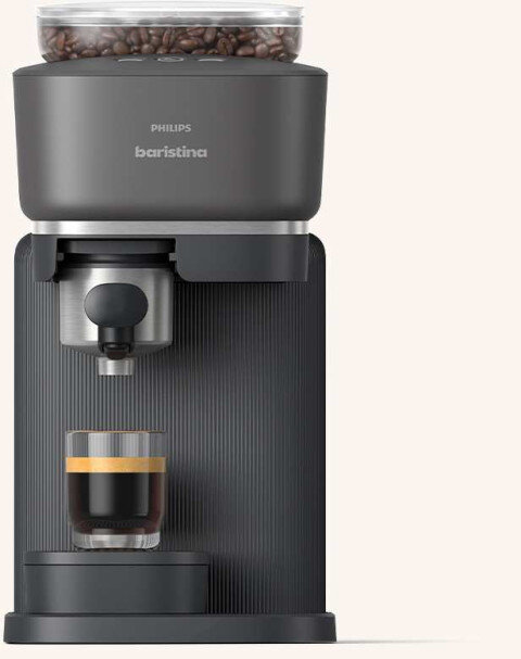 Na obrazie widoczny jest ekspres do kawy z logo \'PHILIPS baristina\', z przezroczystym pojemnikiem na ziarna kawy na górze. Pod dyszą znajduje się szklanka z czarną kawą i pianką.