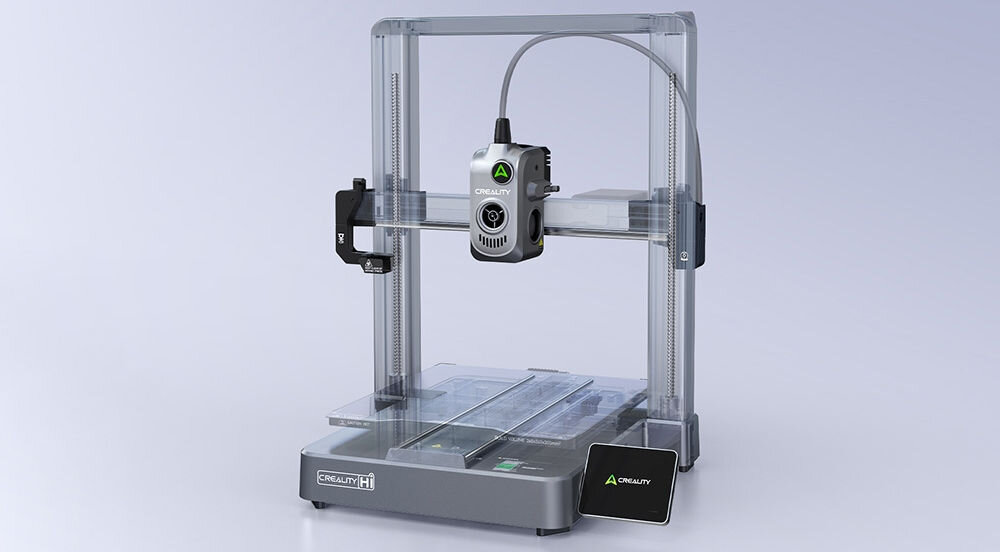 Na obrazie widoczna jest drukarka 3D z logo \'CREALITY\' na obudowie. Urządzenie ma metaliczną konstrukcję i przezroczystą obudowę wokół platformy roboczej.