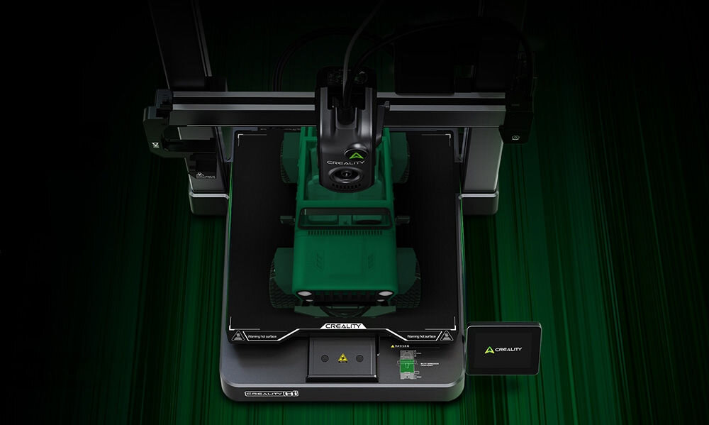 Na obrazie widoczna jest drukarka 3D z modelem zielonego pojazdu terenowego na platformie roboczej. Na urządzeniu znajduje się logo \'CREALITY\'.