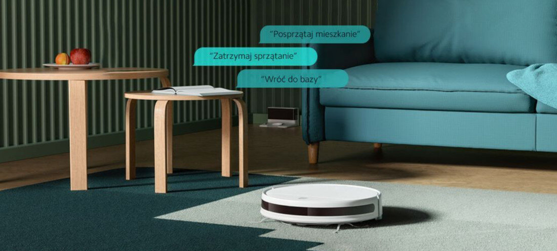 Na dywanie w salonie znajduje się biały robot sprzątający. Obok niego widoczne są trzy dymki z tekstami: \'Posprzątaj mieszkanie\', \'Zatrzymaj sprzątanie\', \'Wróć do bazy\'.